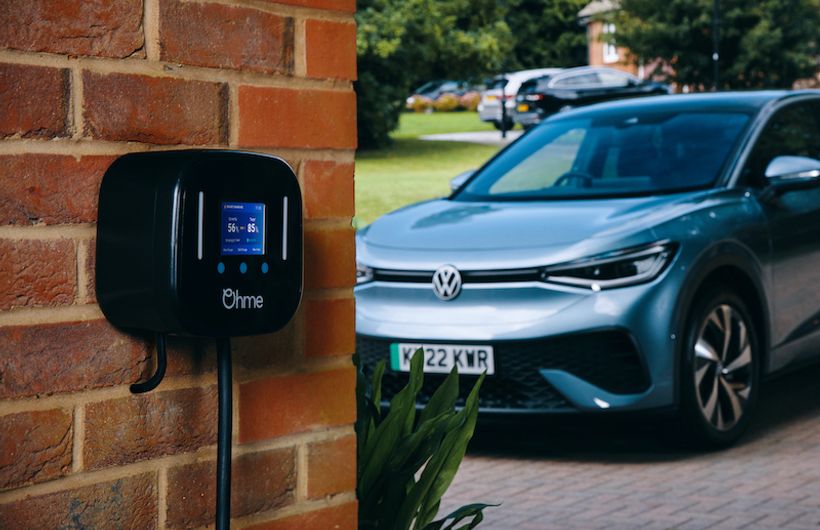 Ohme charger mounted on brick wall, VW ID4 in background